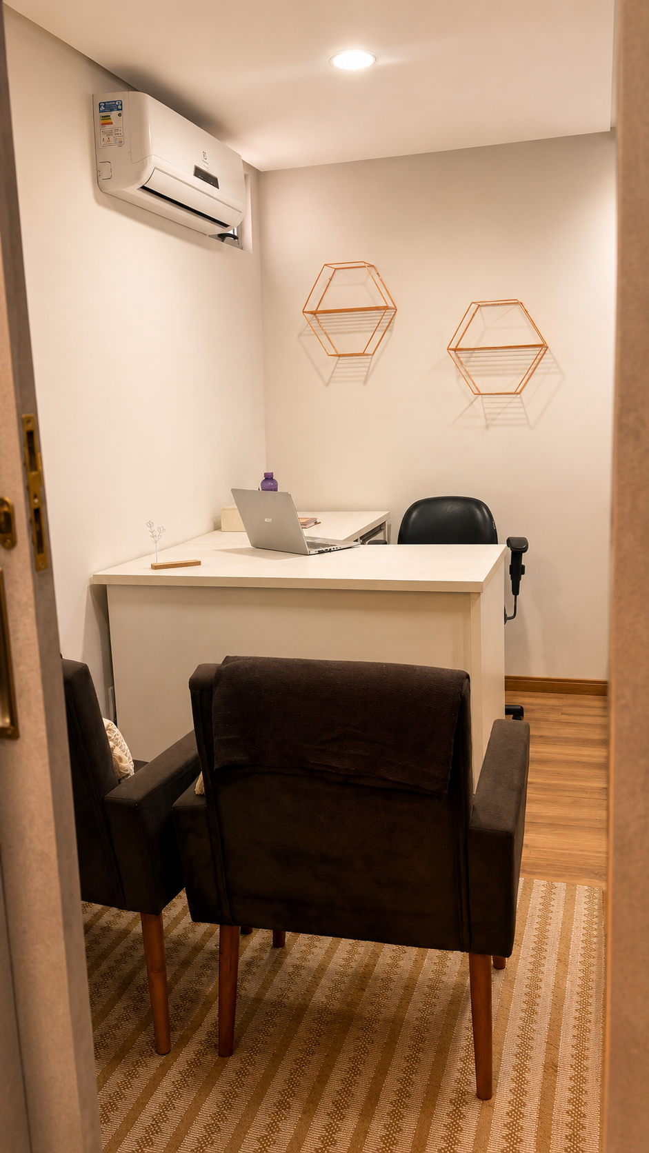 Sala de atendimento com mesa, poltronas e notebook